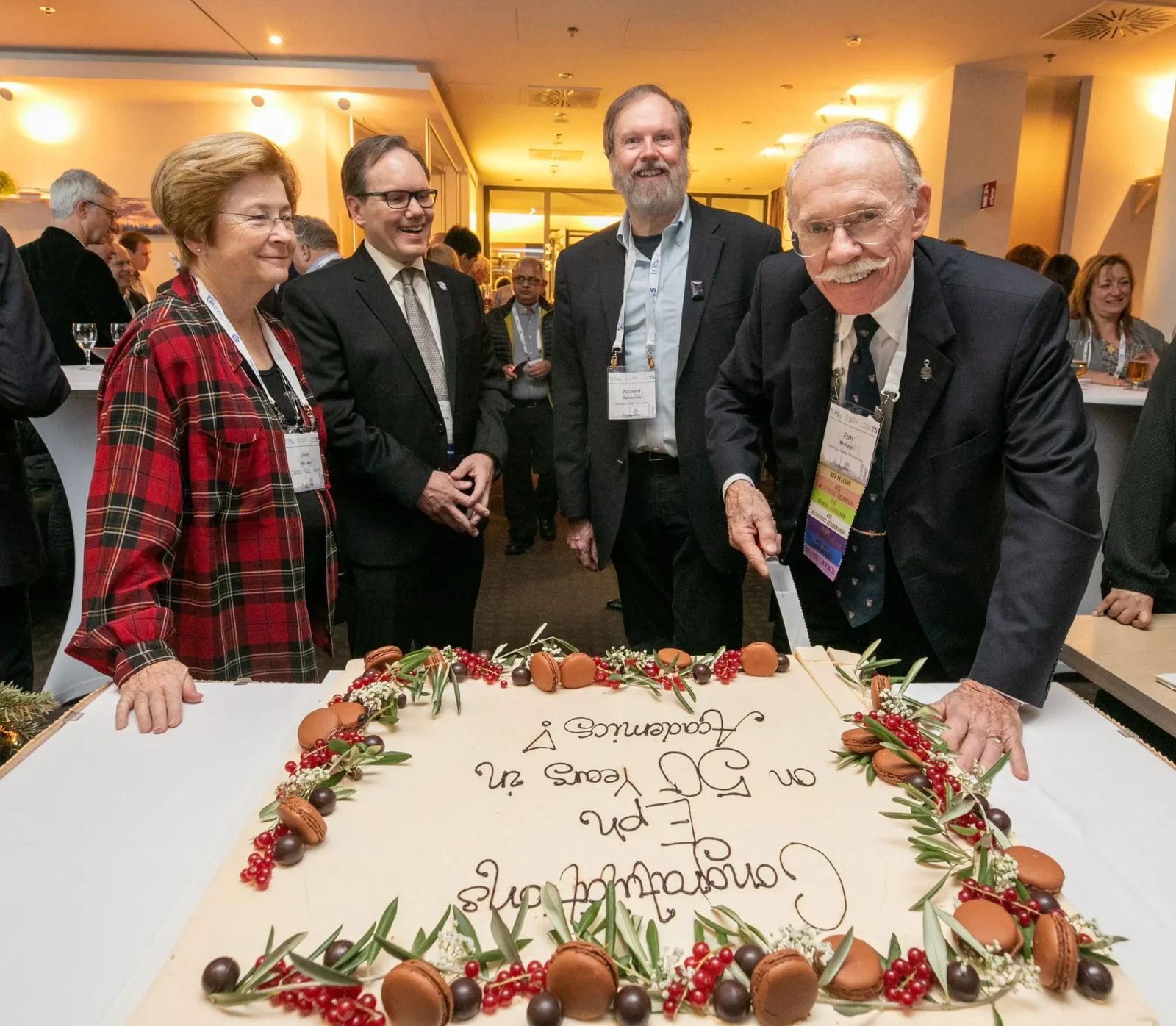AIS members celebrating a colleague's 50 years in academia with a cake