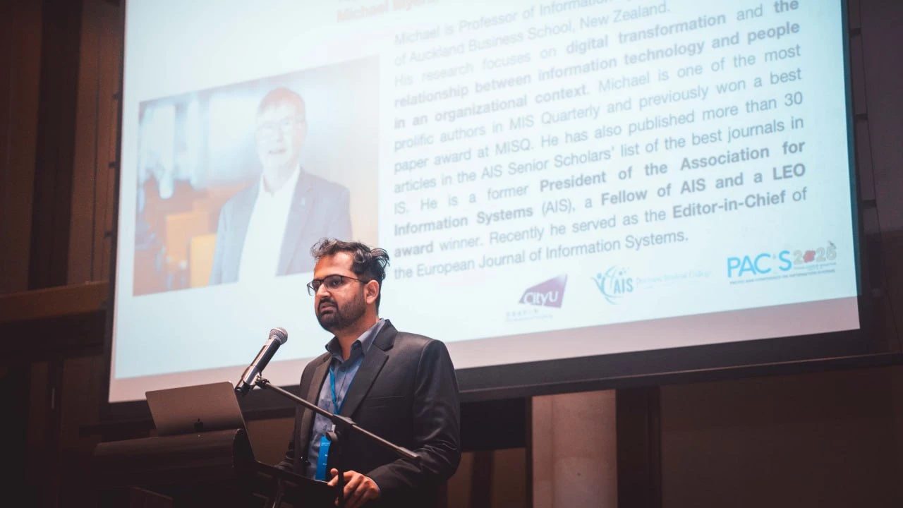 A speaker at a lectern introducing a keynote at the AIS PACIS conference