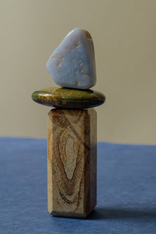 Three smooth stones balanced on a block of banded jasper